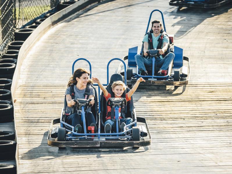 A family of three riding on a go kart track
