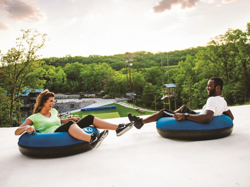 An interracial couple slides down on inner tubes on the Snow Flex attraction