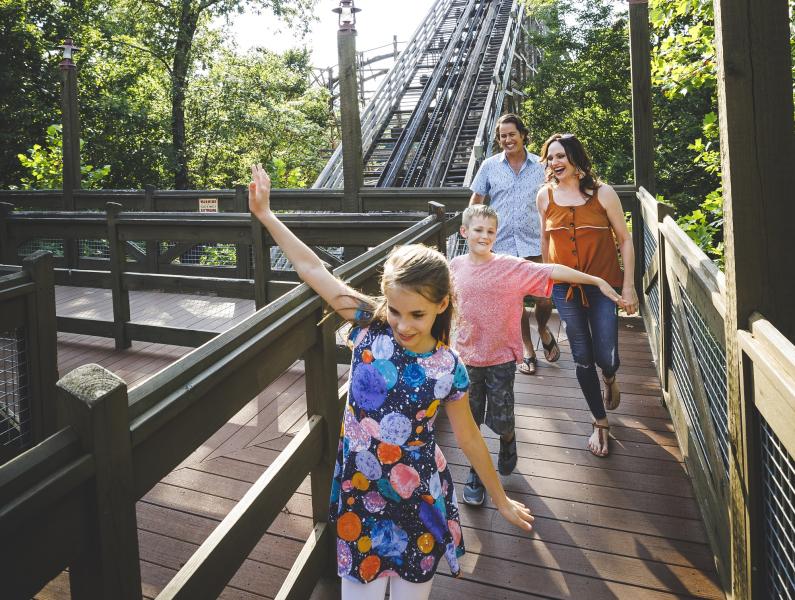 Family enjoying a nice spring day at silver dollar city, a rollercoaster can be seen behind them