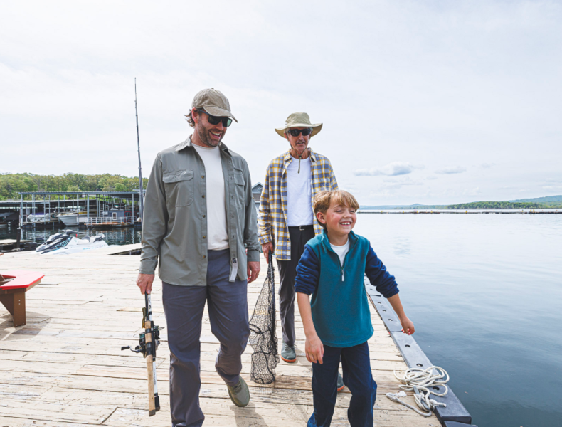 Father, son, and grandfather with fishing gear on a dock by the Table Rock Lake