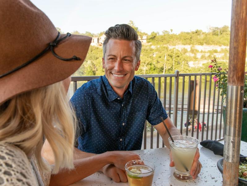 A couple smiling at one another sitting on the balcony at Cantina Laredo