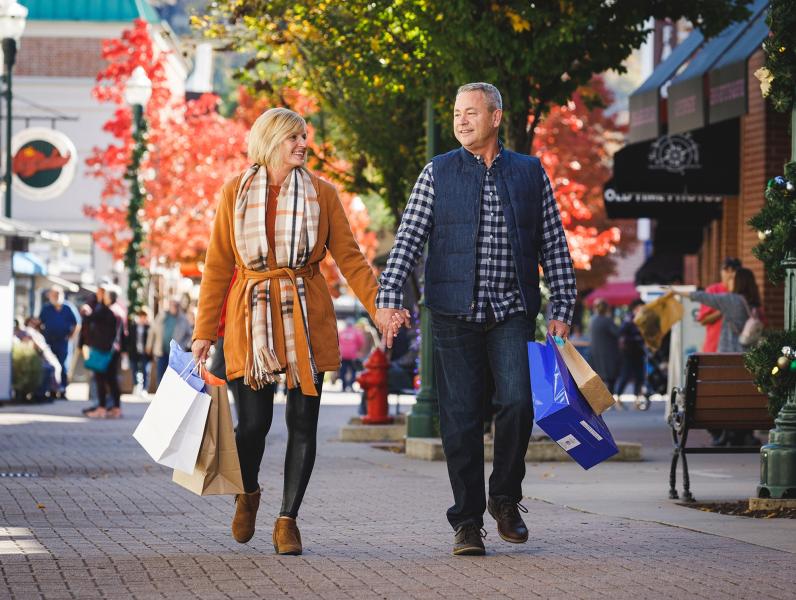 A couple walks down the Branson Landing with shopping bags in hand