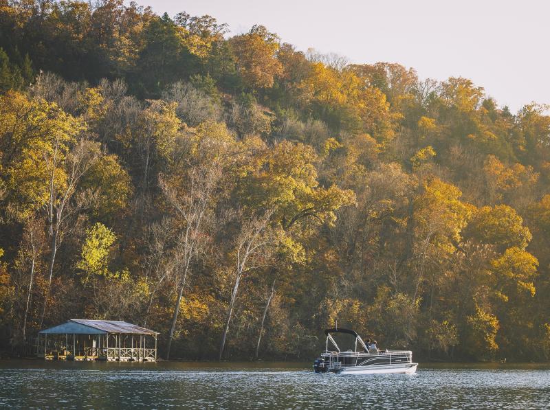A couple on a boat with fall colored trees surrounding them
