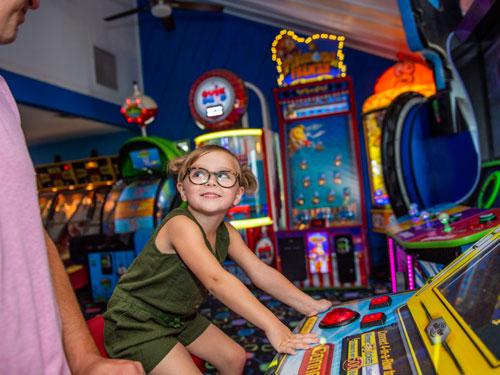 Father and daughter playing games in an indoor Branson arcade.