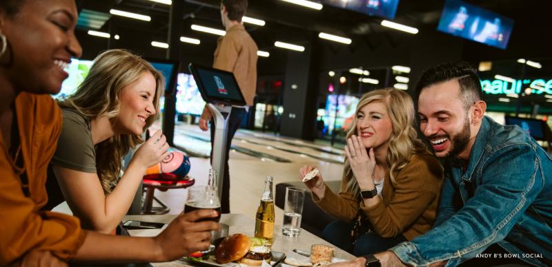Group of friends eating and drinking at a bowling alley night club.