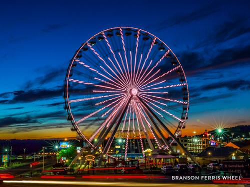 Well-lit Branson Ferris Wheel and surrounding Entertainment District at night.