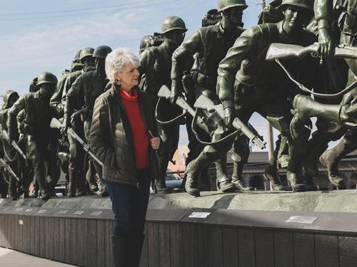 Woman Army veteran looking at a monument of fellow soldiers in Branson. 