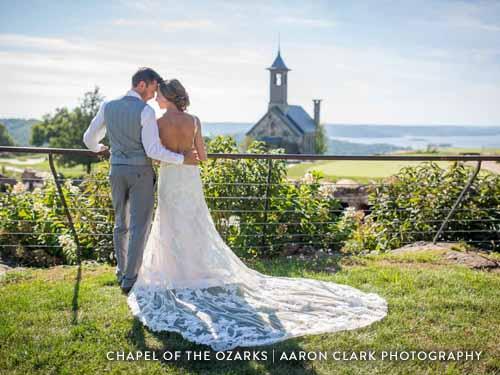 Newlyweds hugging in front of a large chapel on an Ozark golf course.