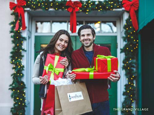 Man and women holding Christmas gifts and shopping bags at Grand Village