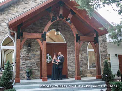 Couple standing in front of a stone chapel after their wedding ceremony.