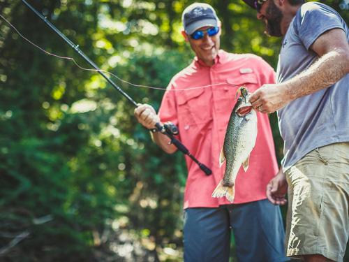 Two men showing off fish on fishing boat in Branson.