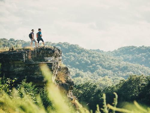 man and woman on a hike standing on the ledge of a scenic pathway in Branson.