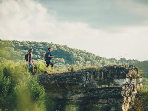 Man and woman standing of the edge of a rock ledge during a scenic hike in Branson.