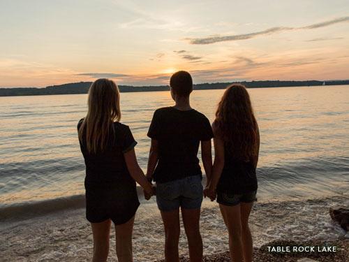 Three girls staring into the sunset at Table Rock Lake.