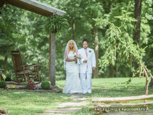 Bride being walked down the aisle at a wooded wedding venue.