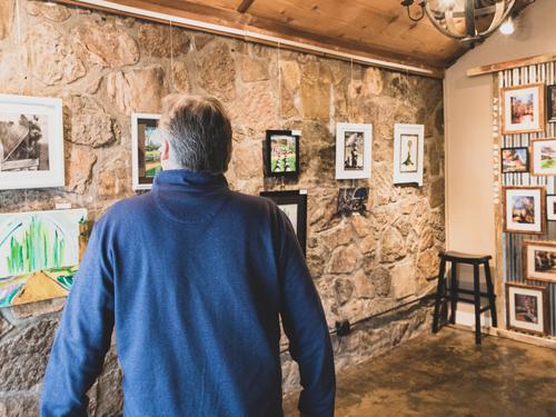 Man walking through art gallery displaying local art from Branson. 