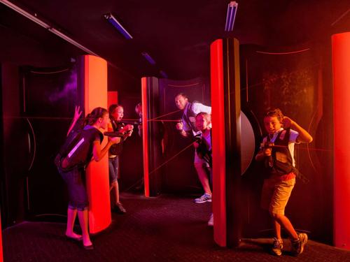 Family playing indoor laser tag in a black light room in Branson.