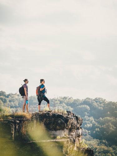 man and woman on a hike standing on the ledge of a scenic pathway in Branson.
