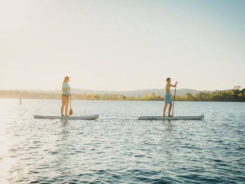 Man and women paddleboarding during sunset on a Branson lake.