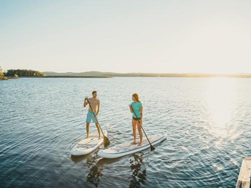 Man and woman paddleboarding on a lake in Branson.