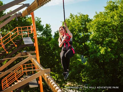Femme grimpant à travers un parcours de cordes en plein air à Branson.