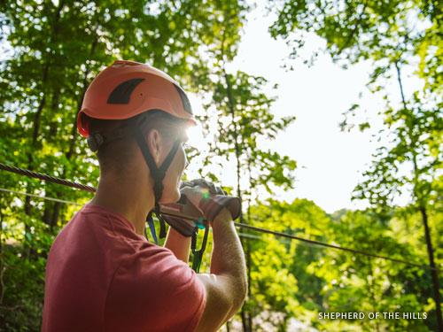 Man riding on outdoor zipline at an adventure park in Branson.