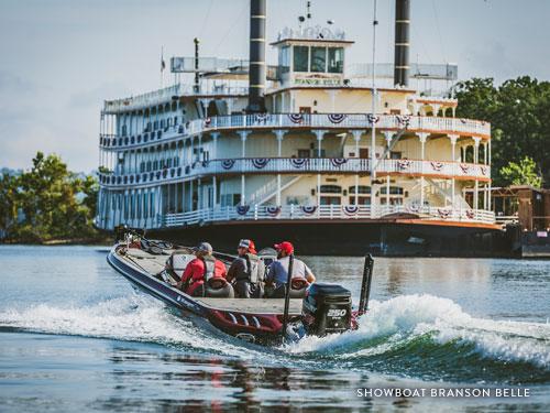 Three men on fishing boats driving beside large Showboat Branson Belle boat on Table Rock Lake in Branson.