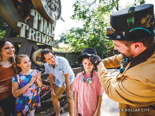 Family interacting with Silver Dollar City character at Time Traveler roller coaster. 