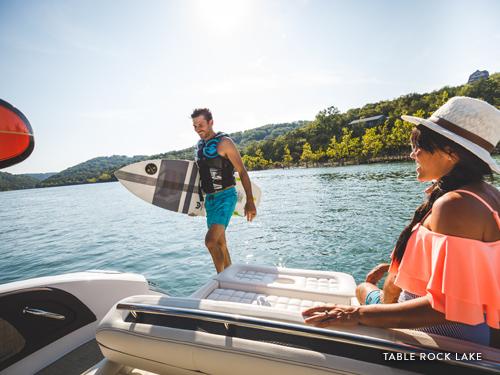 Man holding wake board and woman watching while on a boat on Table Rock Lake in Branson.