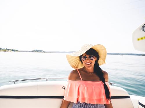 Woman sitting on boat with sun hat at a lake in Branson.