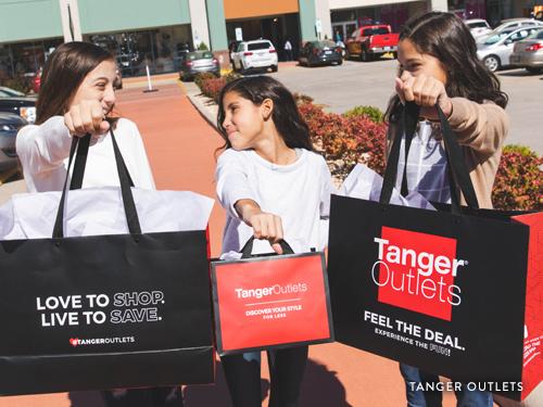 Three sisters holding shopping bags from Tanger Outlets in Branson.