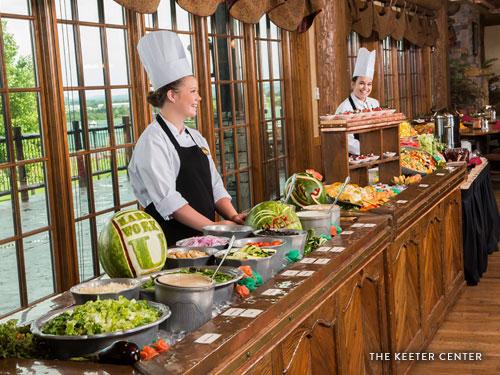Two college students serving guests food at a buffet-style restaurant in Branson.