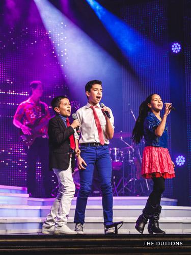 Three young performers singing on a Branson stage.