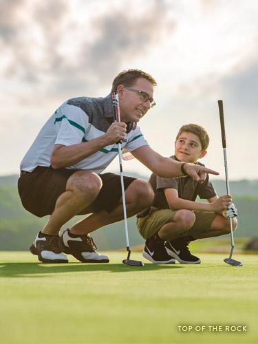 Father and son reading a putt on a golf course in Branson.