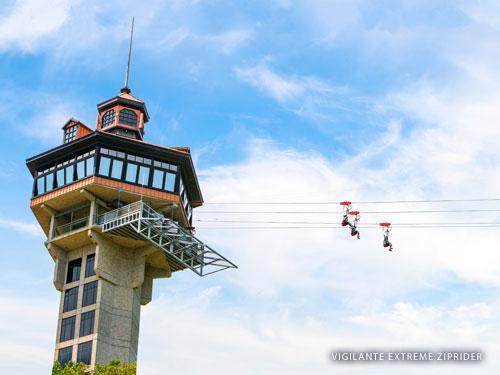 Three zipline riders sliding down a zipline from a tall tower in the Ozark Mountains.