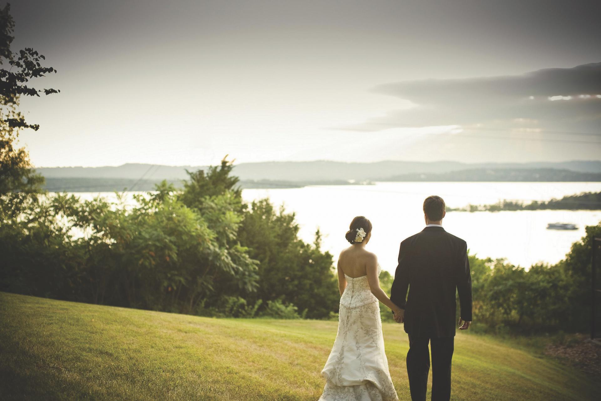 Bride and groom looking into the distant scenery of a lake and rolling hills at Chateau on the Lake Resort.