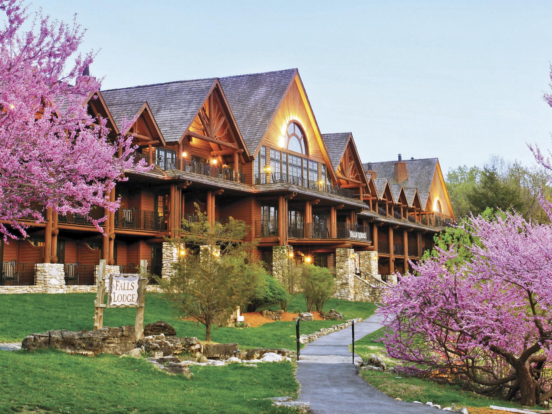 Exterior of Big Cedar Lodge with pink blossoms on trees.