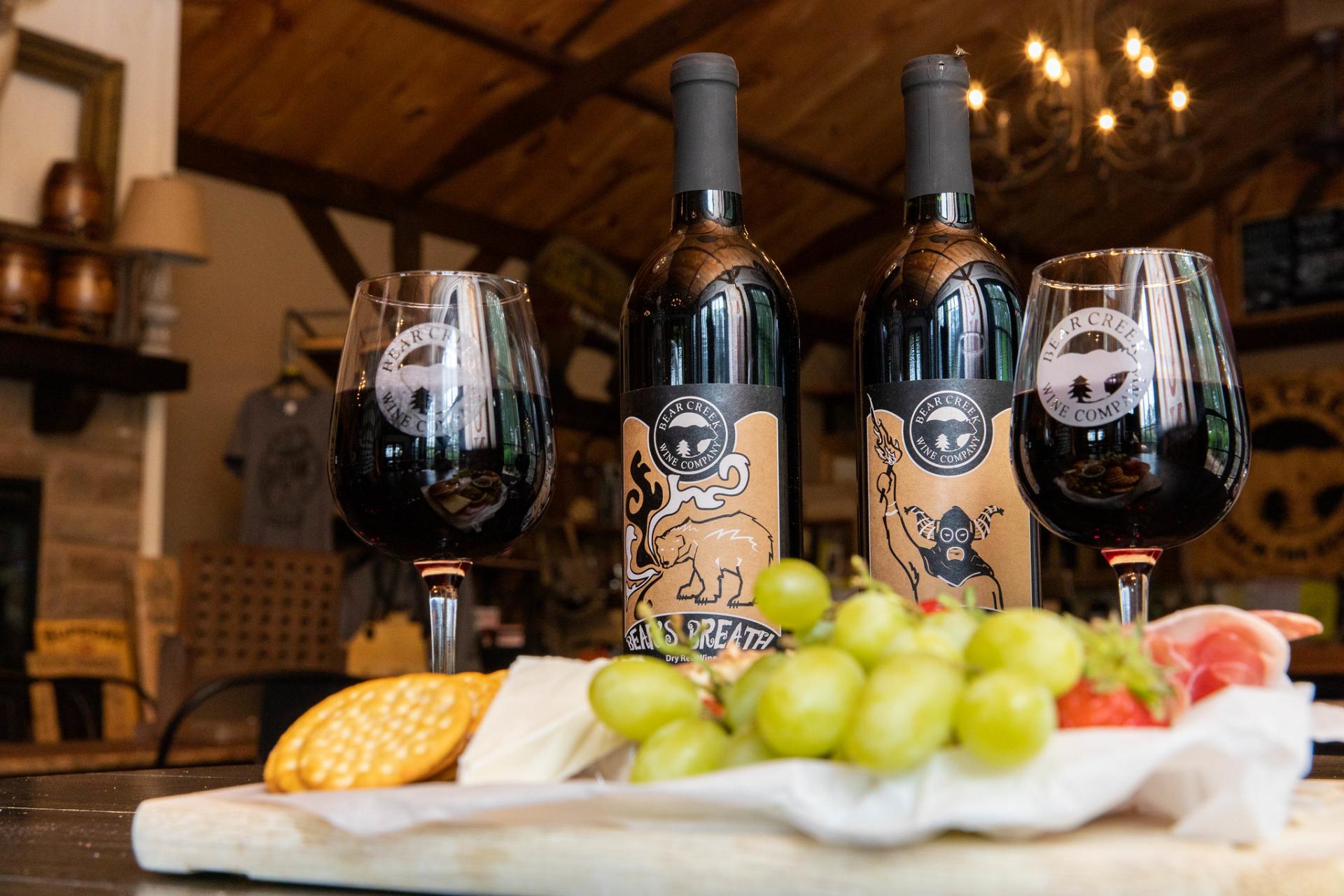 Two wine glasses and two wine bottles with a charcuterie tray.