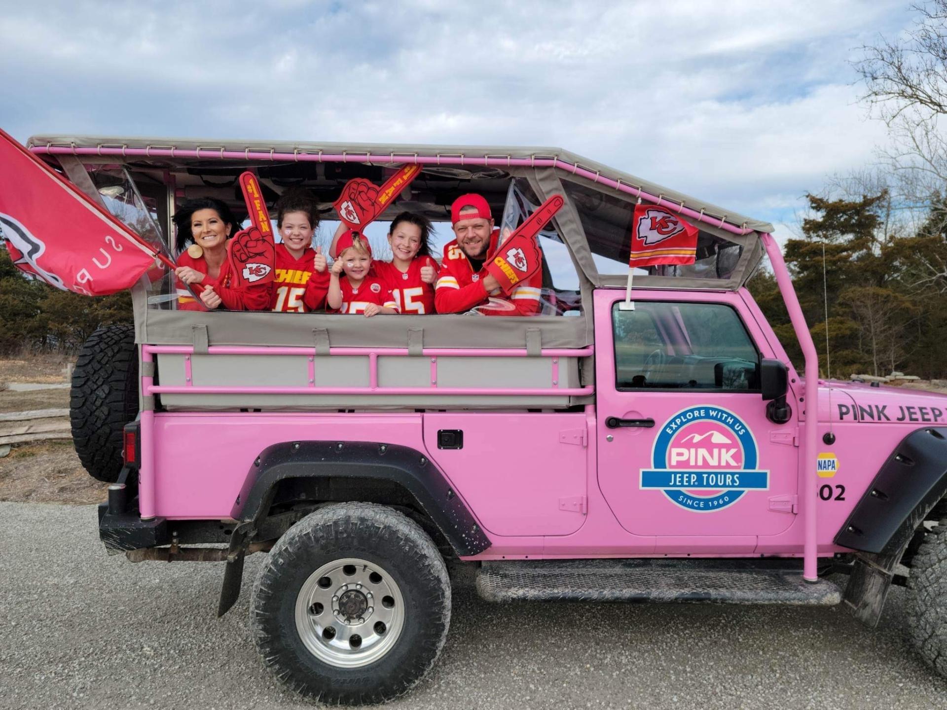 family in kansas city chiefs gear riding in pink jeep