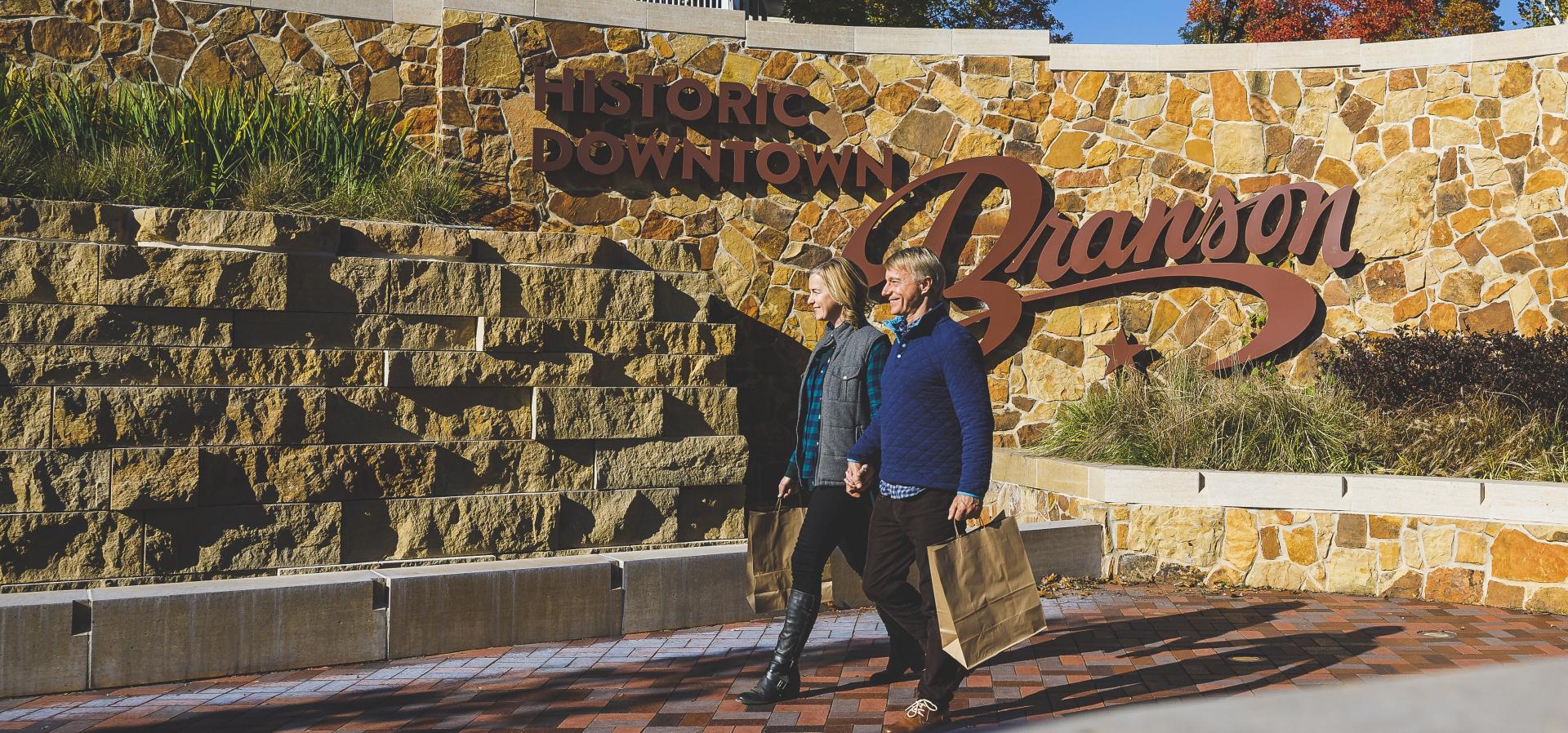 On a fall day, a couple walks through downtown Branson with shopping bags in hand