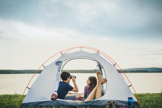 Two kids in a camping tent looking out at a Branson lake.