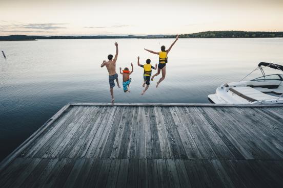 Family of four jumps into Table Rock Lake from dock near boat.