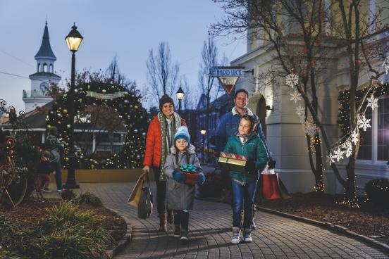 Family of four carrying shopping bags and Christmas gifts at Grand Village Shops in Branson, Missouri.