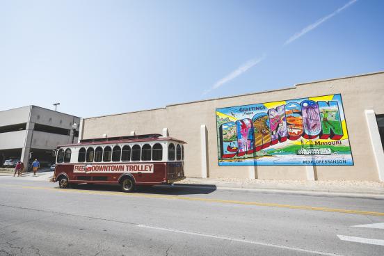 downtown branson trolley in front of branson postcard mural