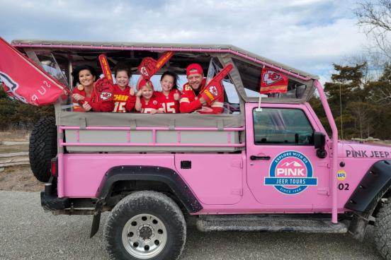 family in kansas city chiefs gear riding in pink jeep