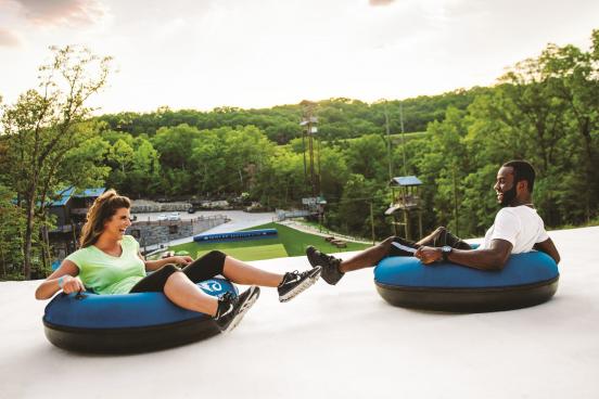 An interracial couple slides down on inner tubes on the Snow Flex attraction