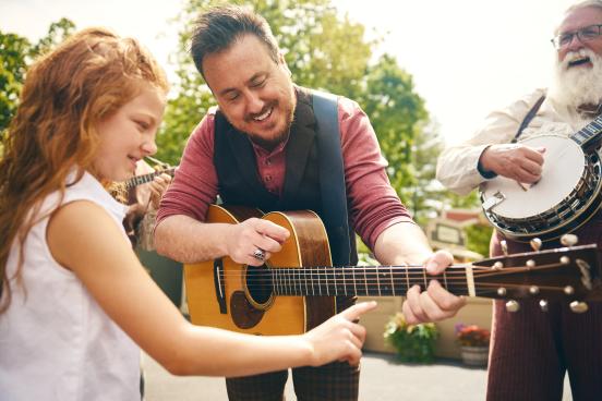 A little girl strums a performers guitar at Silver Dollar City