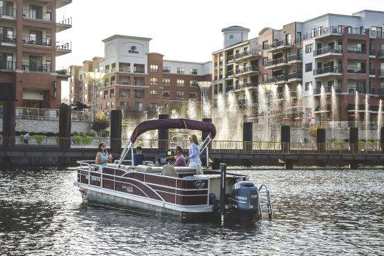 A family on a boat on lake taneycomo in front of the Branson Landing