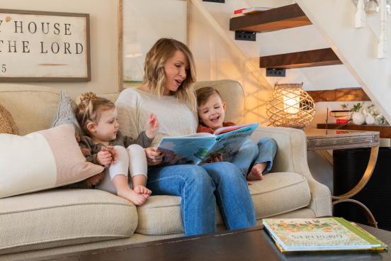Woman reading a book to her two children inside their home in Branson.