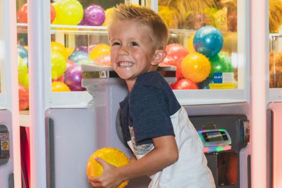 Young boy excited about winning a prize at a claw machine in an arcade.